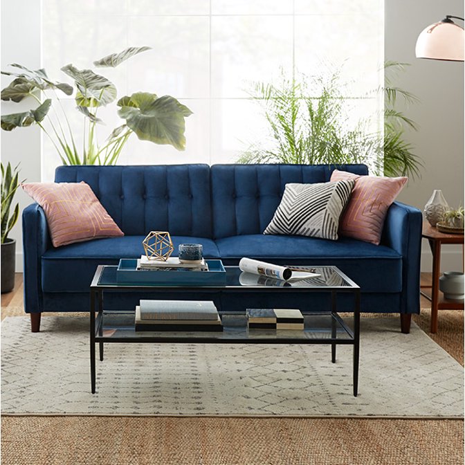 A blue mid century sofa in a boho living room.